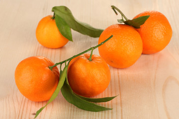 Sweet tangerines with leaves, on wooden background