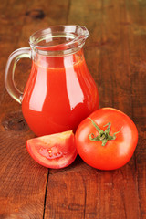 Full jug of tomato juice, on wooden background