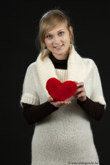young woman with hart shaped pillow on black
