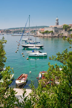 Boats on little port beside Krk old town view with vegetation -
