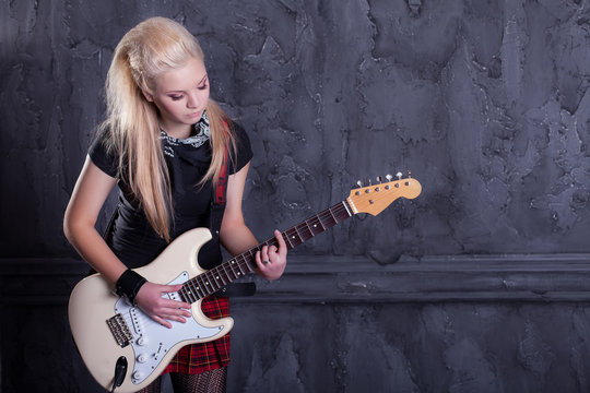 teenager rockstar with electric guitar against wall background