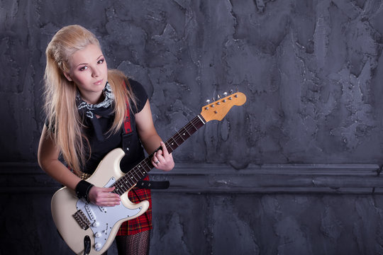 teenager rockstar with electric guitar against wall background