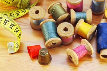 Reels of thread  tapeline and two thimbles on wooden table