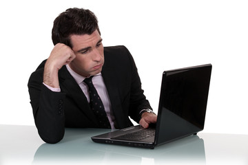 Annoyed businessman working on his laptop