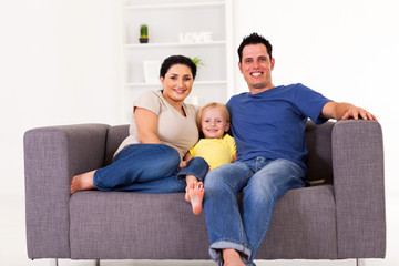 Fototapeta na wymiar young happy family sitting on sofa at home