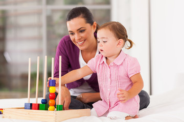 little girl playing educational toy with mother on bed