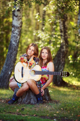 Hippie girls with guitar sitting on the stump