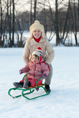   child on sled with mother in winter