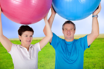 Man and woman holding up exercise ball