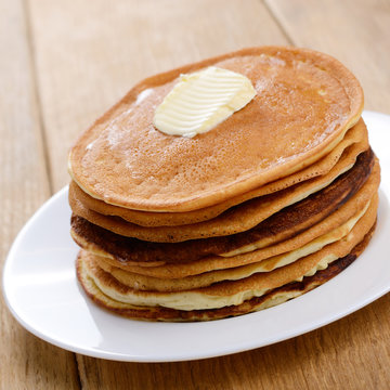 White plate with pankakes stack on the wooden table