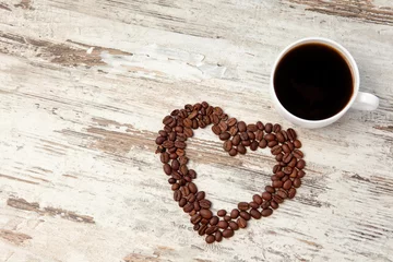 Foto auf Acrylglas Kaffee Bar Körner und eine Tasse Kaffee auf einem Holztisch
