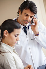 Doctor Attending Call While Standing With Colleague