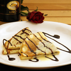 Pancakes with chocolate sauce and eggnog served on a plate