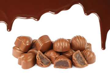 Melted chocolate dripping with candies on white background.