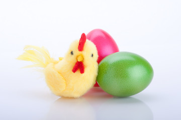 drei gelbe Küken mit bunten farbigen Ostereiern vor weiß