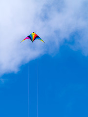 A rainbow colored stunt kite against a blue sky