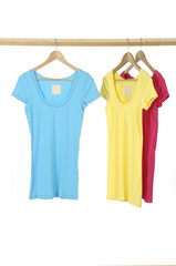 Three different female shirts on wooden hangers