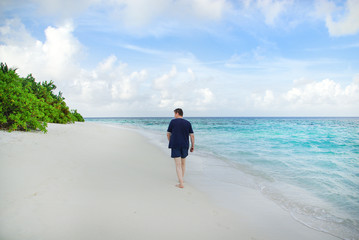 Young man on white sand beach on Maldives