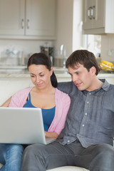 Young couple relaxing on the couch while using the laptop