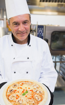 Smiling chef showing pizza