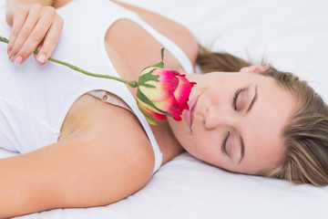 Obraz na płótnie Canvas Blonde kobieta leżącego na łóżku z różą