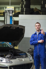 Mechanic by car gesturing thumbs up