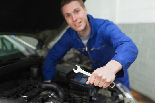 Auto mechanic with spanner repairing car