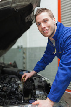 Auto mechanic checking car engine oil