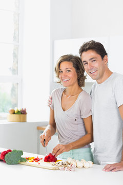 Smiling wife chopping vegetables with husband