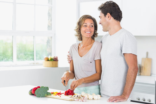 Husband embracing wife as she prepares vegetables