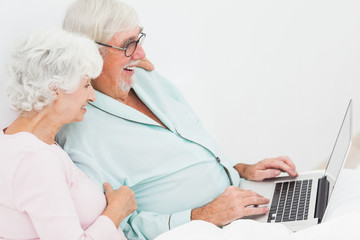 Couple with laptop in bed