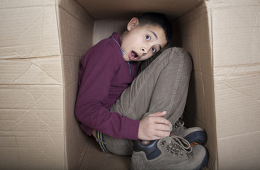 Teenage boy hiding in cardboard box