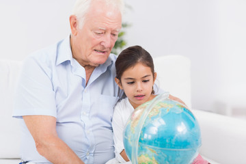 Obraz premium Granddaughter and grandfather with globe