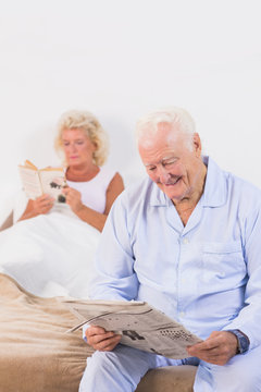 Smiling elderly couple reading on the bed