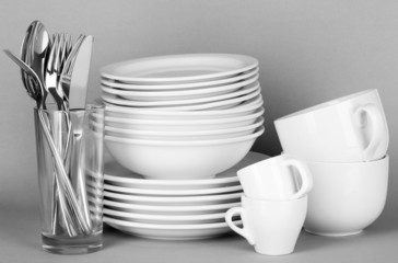 Clean white dishes on grey background © Africa Studio