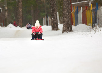Little boy and girl  slides down from the snow hill on a sledge