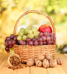 Grape in basket with nuts on wooden table
