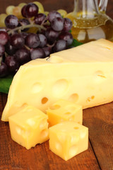 Cut cheese with grape on wooden table