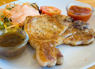Grilled pork chops with vegetables, salad and dipping saurce