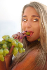 young beautiful woman on the beach with grapes