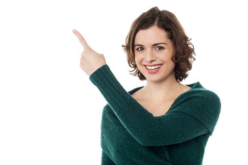 Charming woman pointing towards copy space area