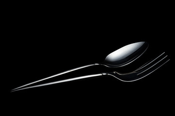 Silver metal spoon and fork on the black background