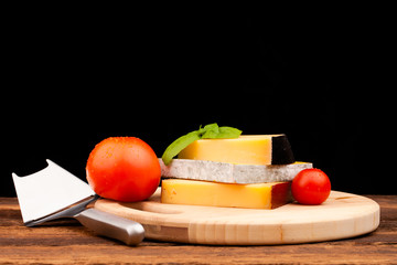 Various types of cheese and tomatoes isolated on black