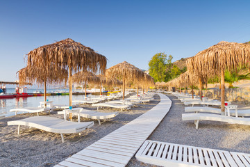 Sunbeds under parasol on the public beach of Crete, Greece