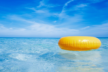 floating yellow ring on crystal blue sea water with sky, shallow