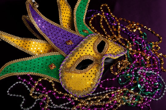 A Mardi Gras Jester's Mask With Beads On A Black Background