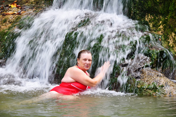 Happy fat female in red swimsuit resting in a water