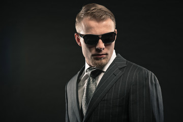 Fashion man in suit wearing sunglasses. Studio shot.