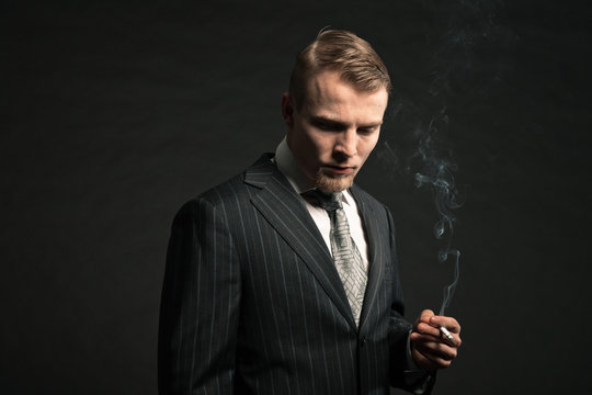 Fashion man in suit smoking cigarette. Studio shot.