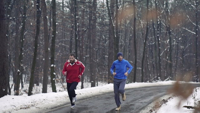 Men jogging in the forest in winter, super slow motion